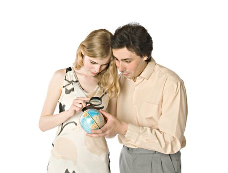 A couple looking at a small globe through a magnifier