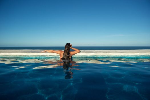 Woman relaxing on a swimming pool with a sea view in Arraial d'Ajuda, Bahia, Brazil, Nikon D3S, RAW shooting