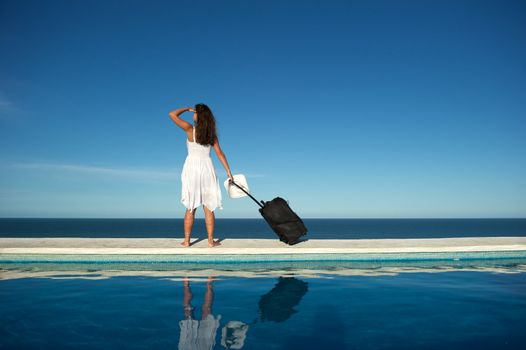 Traveler with heavy baggage walking on a swimming pool with sea view in Arraial d'Ajuda, Bahia, Brazil, Nikon D3S, Nikon AF-S 24-70, RAW shooting.