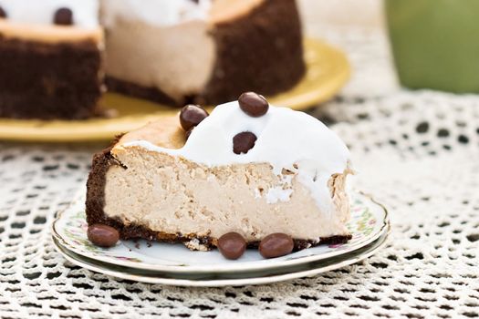 Rich cheesecake with chocolate graham cracker crust and garnished with whipped cream and chocolate covered coffee beans.