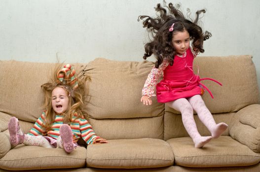 two little girls jumping on sofa, motion blur on some places