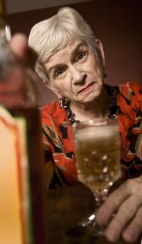 Senior woman alcoholic with a bottle of booze