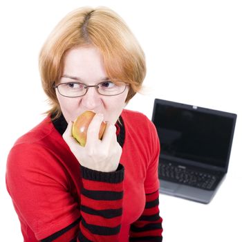 The woman in points bites an apple against the laptop