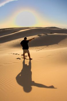 An image of man pointing to the sky in the desert