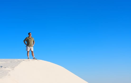 An image of a man atop a sand dune