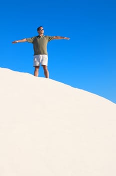 An image of a man atop a sand dune