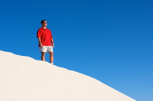 An image of a man atop a sand dune