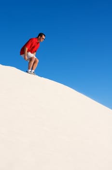 An image of a man about to jump off of a sand dune