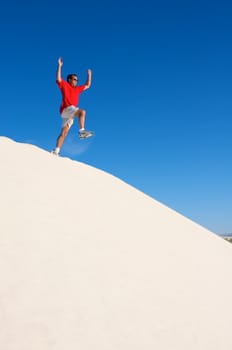 An image of a man jumping off a sand dune