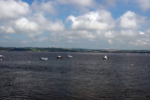 a calm sea on the west coast of ireland with boats anchored in the bay