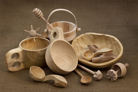 Polish folk wood craft (cups, bowl, spoons, scoops, bucket, kitchen utensils, butter mold, honey drizzler) on burlap background