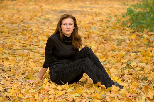 The sad young girl in autumn park during a leaf fall