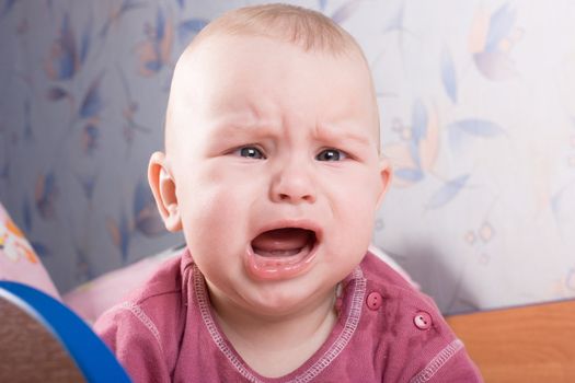 Crying baby into her cot