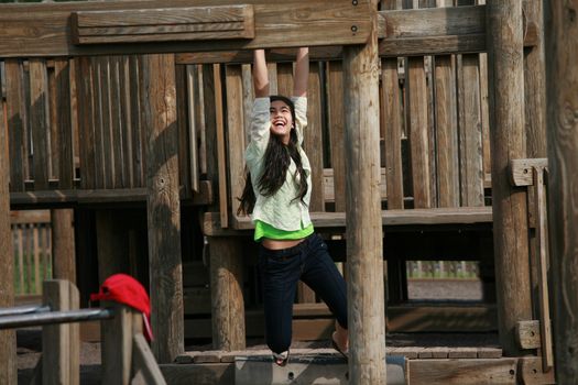 Teenage girl playing at playground on monkey bars