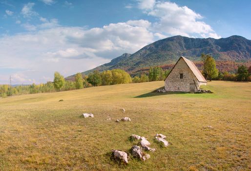 old house on the field over mountains and blue sky