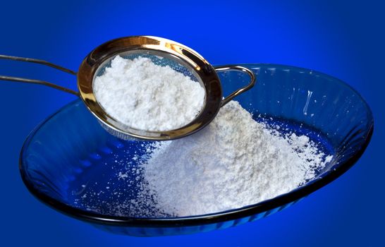 Icing sugar and sieve on a blue background