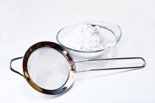 colander and Powdered sugar on white background