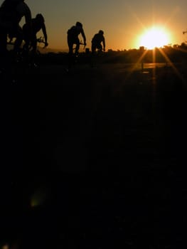 A group of cyclists, biking at sunrise