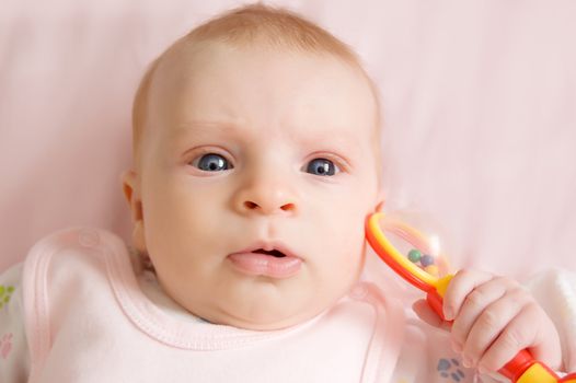 Three months baby girl playing with rattle