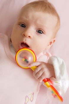 Three months baby girl holding rattle