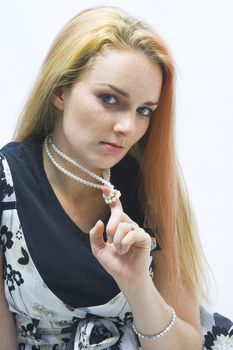 Model gazes at camera as she twists her pearl necklace.