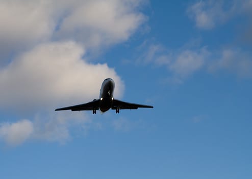 Silhouette of aircraft taking off in blue sky