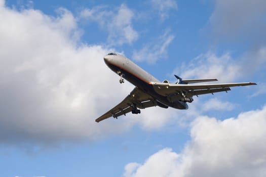 Passenger airplane landing on blue sky with clouds background