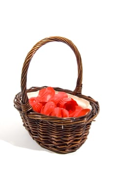 wicker basket filled with red rose peddles on a white background