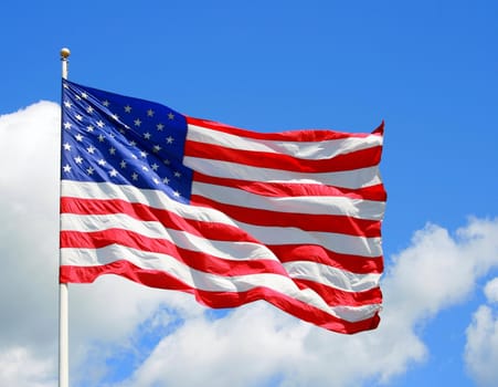 a US flag blowing in the wind under a vibrant blue sky