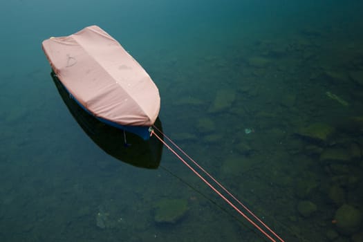 a blu boat in a lake and a red cord