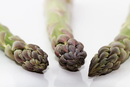 closeup of three green asparagus tips on white background