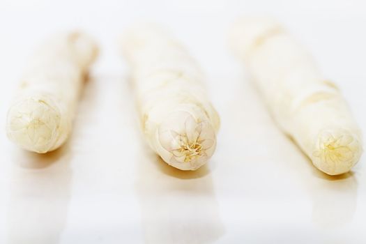 closeup of three tips of asparagus on white background