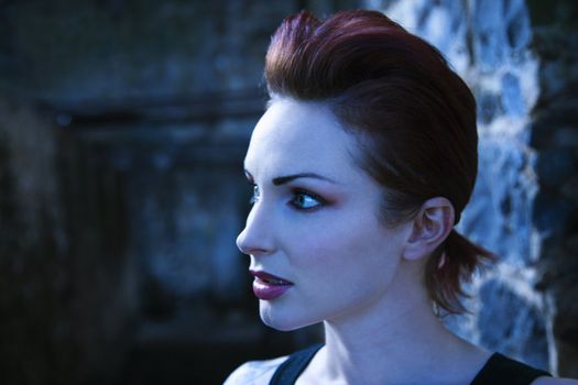 Blue-toned side view portrait of serious looking Caucasian woman.