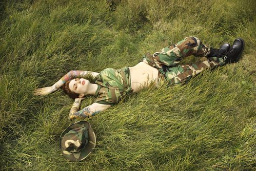 Attractive tattooed Caucasian woman in camouflage lying on grass in Maui, Hawaii, USA.