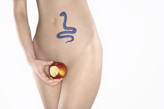 Portrait of nude attractive redhead Caucasian young woman with snake tattoo holding apple.