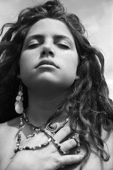 Young adult Caucasian female holding necklace with closed eyes.