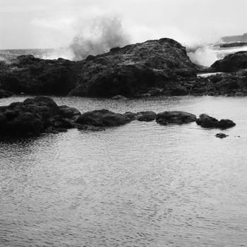 Landscape of waves crashing into rocky Maui Hawaii coast.