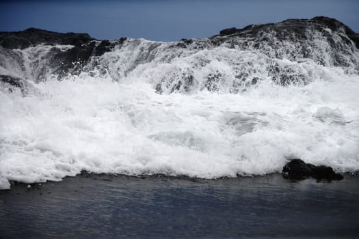 Landscape of waves crashing into rocky Maui Hawaii coast.