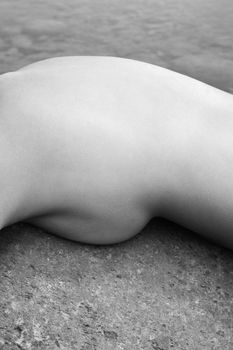 Abstract close up of young Asian female nude lying on rock.