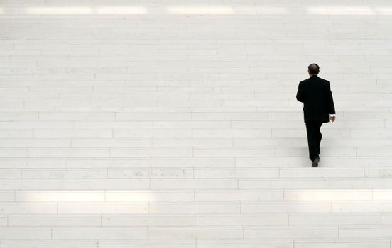 businessman in black suit going along large stairs