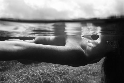 Underwater view of young Asian nude woman floating on back.