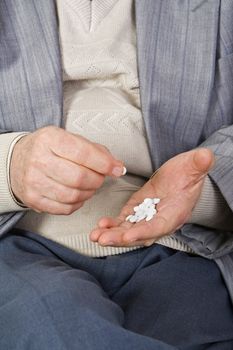 Close-up image of a senior's hands taking pills.