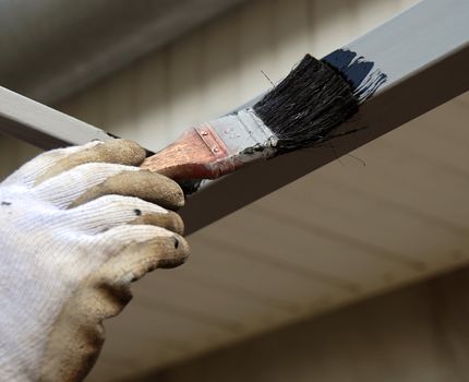 painting brush on metal rod with black paint closeup