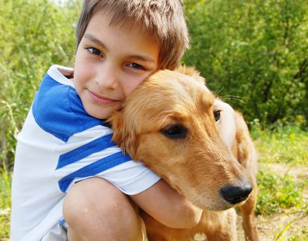 happy smiling little boy hugging his golden retriever dog closeup