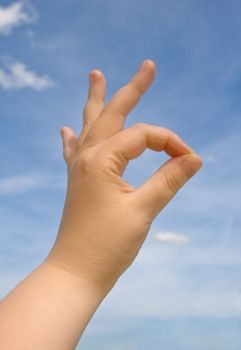 Human hand making OK sign against blue sky