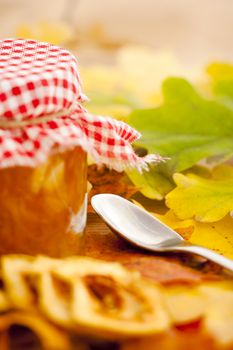 Full jar of apple jam on the leaves