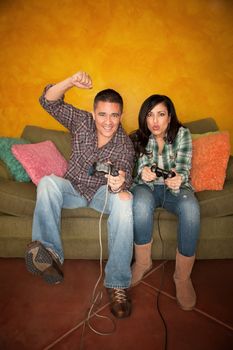 Attractive Hispanic Couple Playing a Video Game with Handheld Controllers