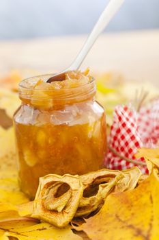 Full jar of apple jam on the leaves