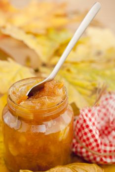 Full jar of apple jam on the leaves