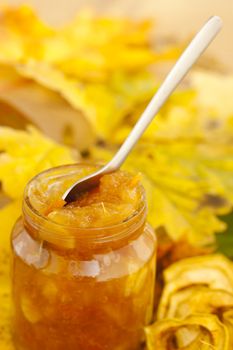 Full jar of apple jam on the leaves